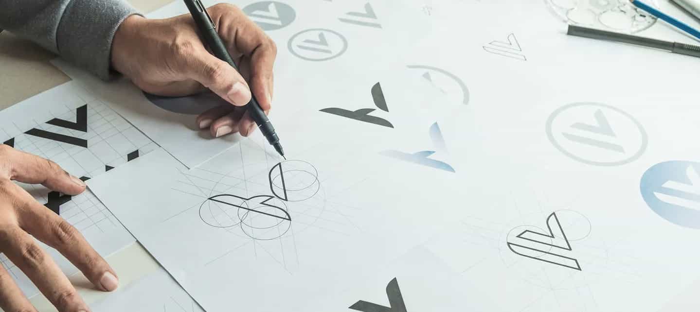 Hånd som tegner logo på tegnebrett