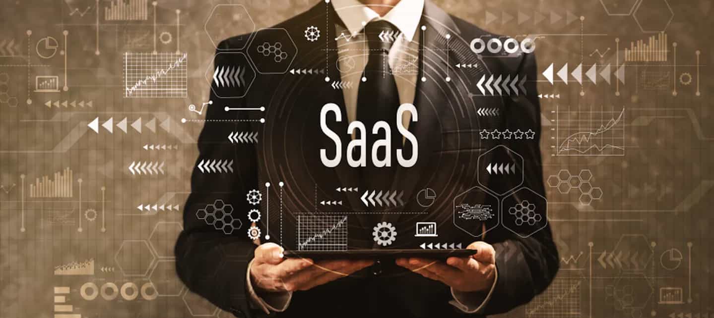 Mann i dress som holder et nettbrett som lyser opp teksten "SaaS" og symboler som illustrer teknologi.