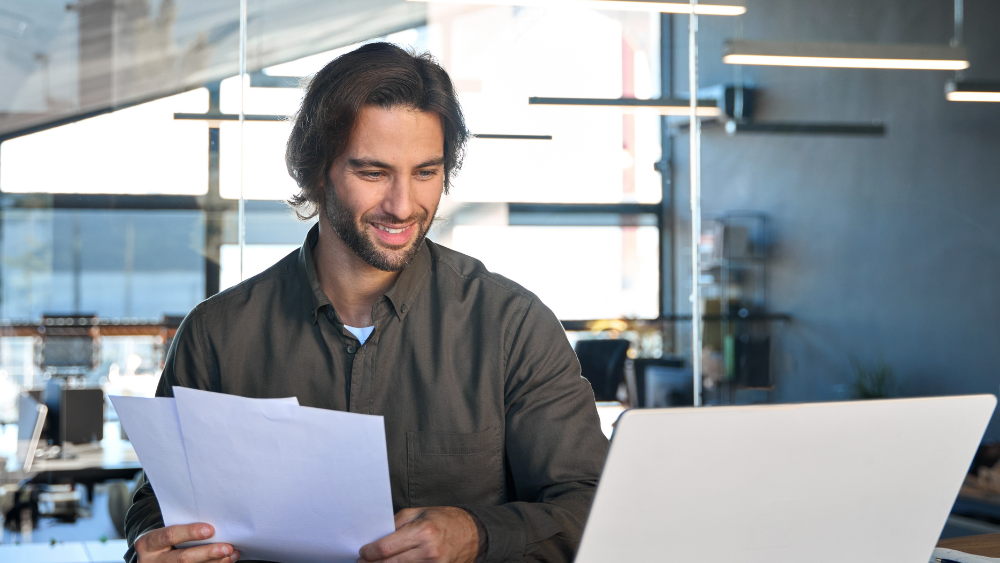 Office professional reading AI paper and laptop