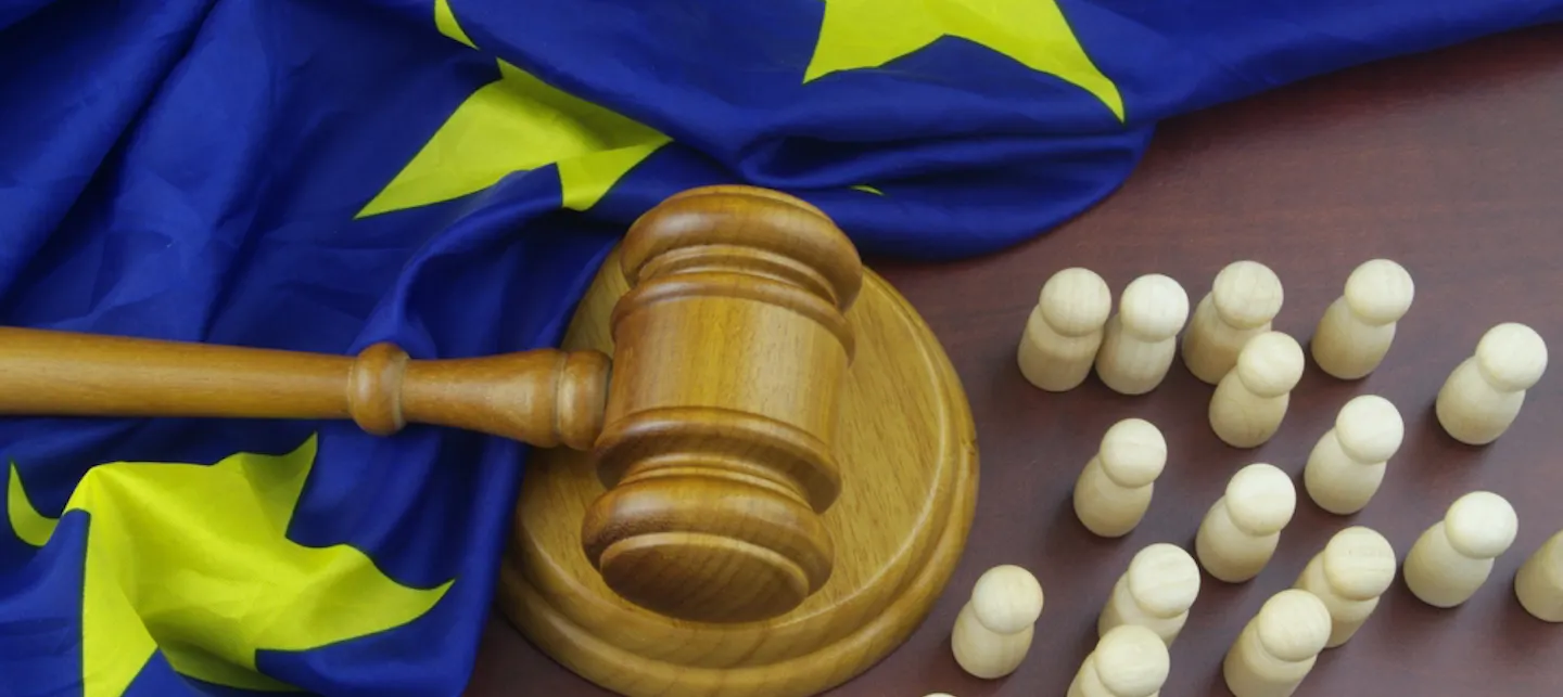 En rettshammer liggende ved siden av et sammenkrøllet EU-flagg. 